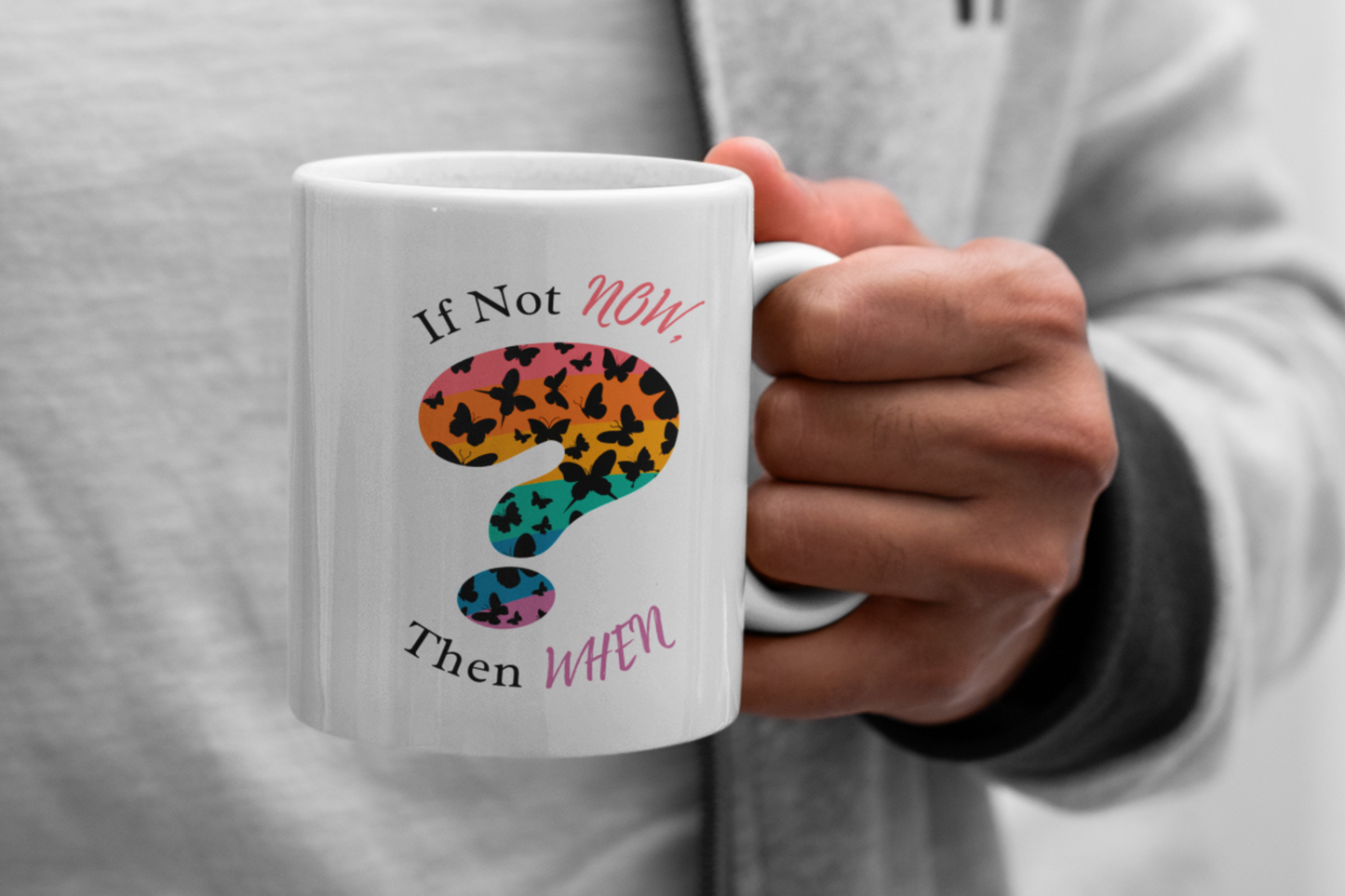 person holding the “if not now, then when?” mug with a rainbow question mark design and text