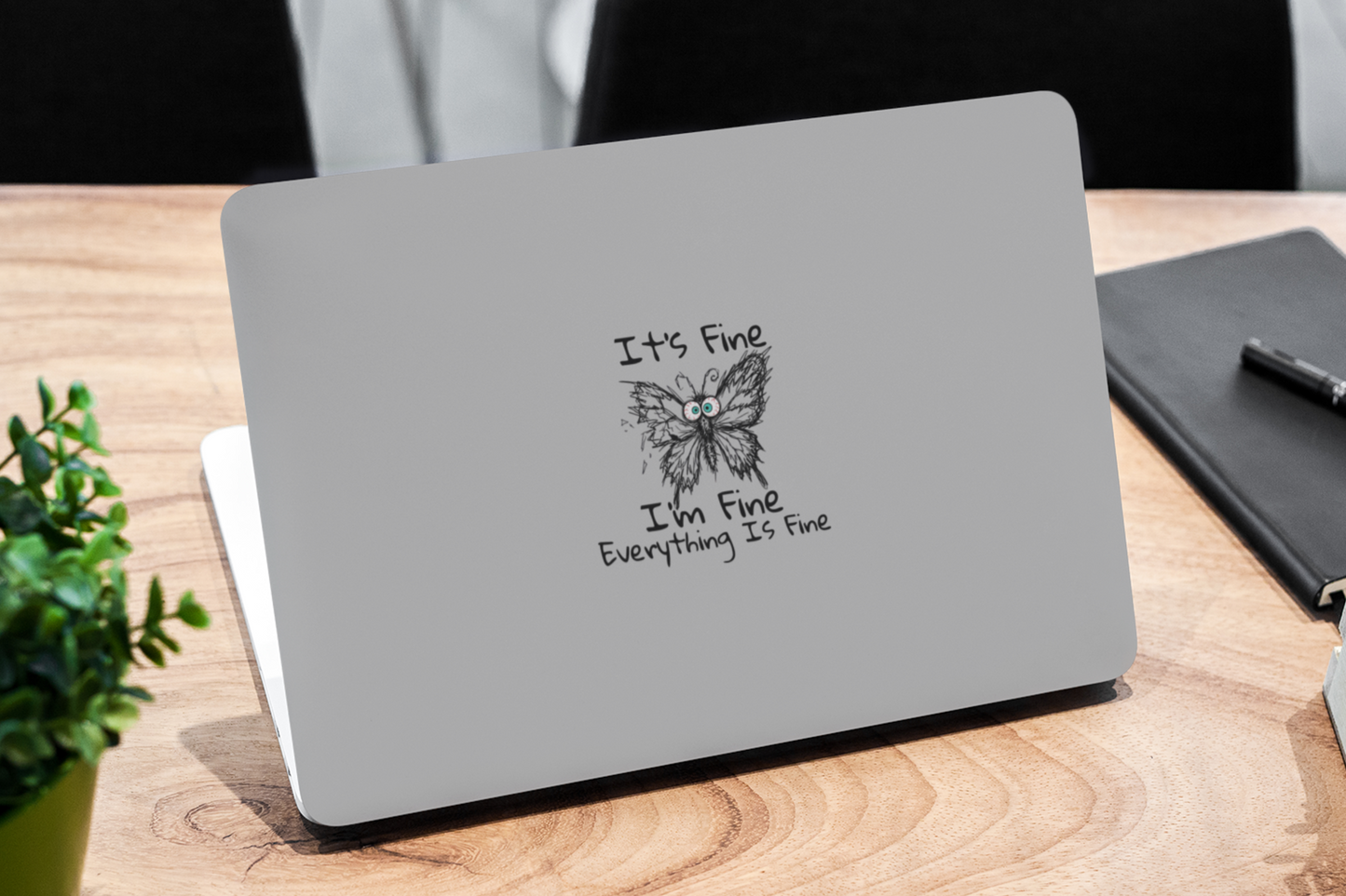 Anxious butterfly vinyl sticker on laptop featuring It's Fine I'm Fine Everything Is Fine text on a wooden desk