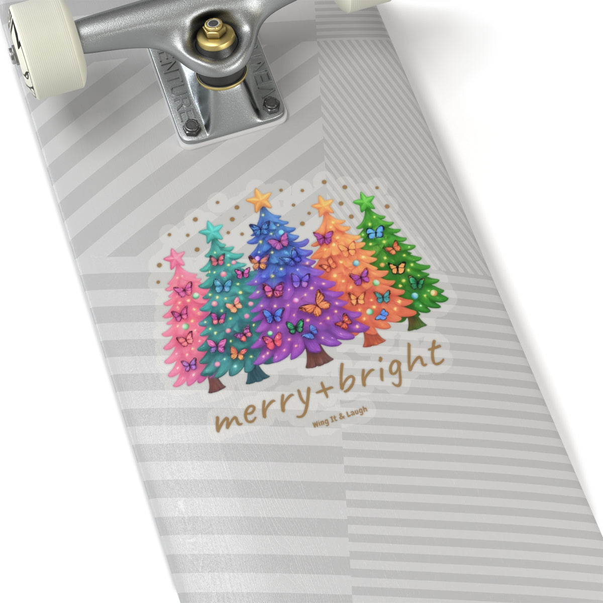 Skateboard with colorful butterflies and Christmas trees design and 'merry + bright' text on a white background