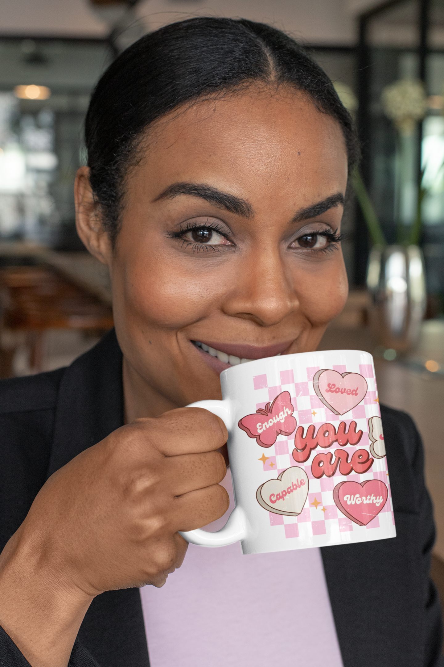 Woman enjoying coffee from an inspirational butterfly affirmation mug with hearts, promoting self love, confidence, and mental health positivity