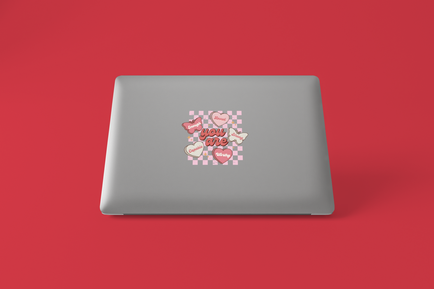 Gray laptop with a decorative sticker on a red background