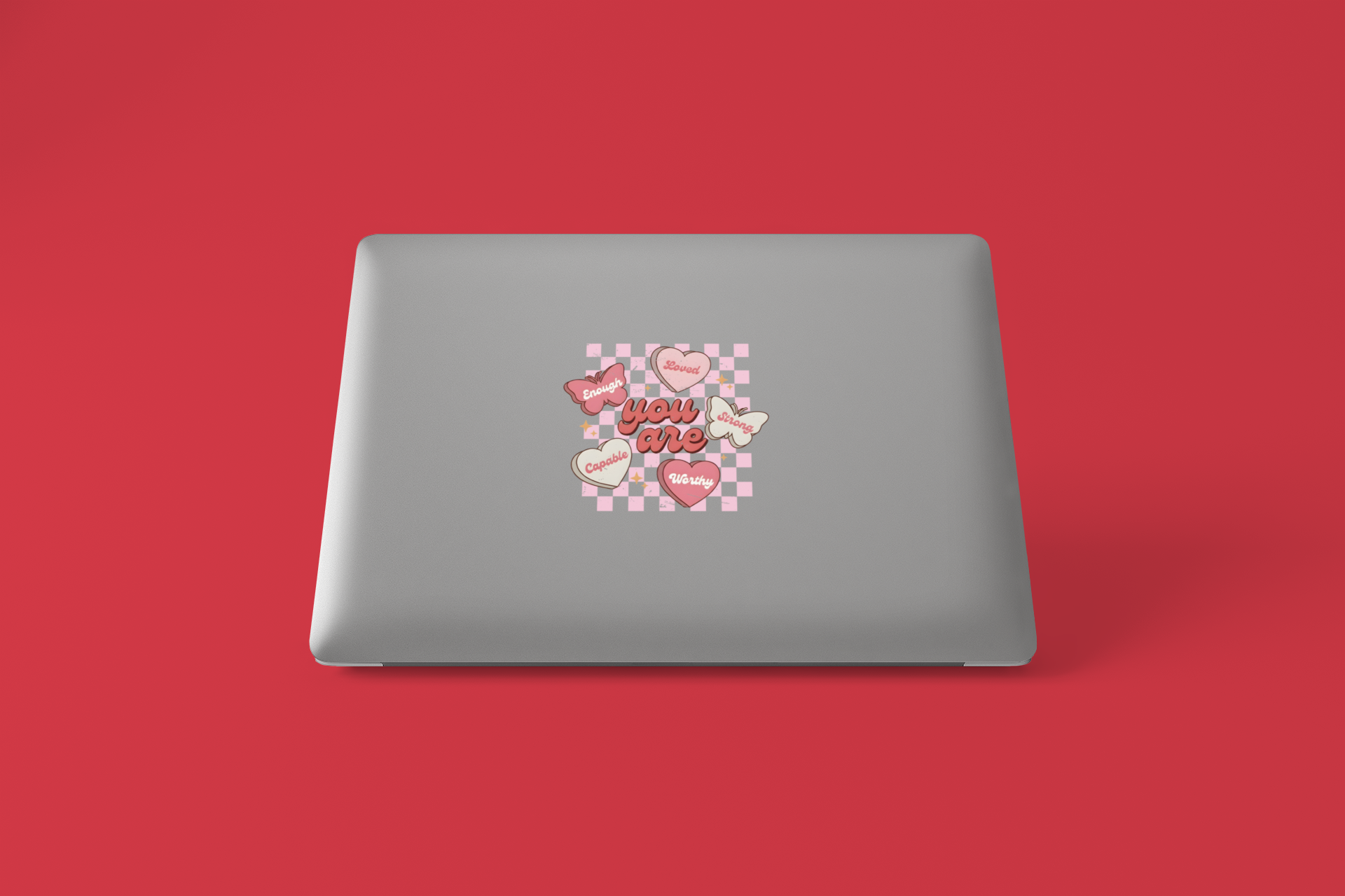 Gray laptop with a decorative sticker on a red background
