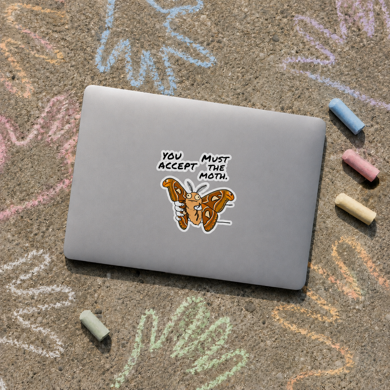 Atlas Moth sticker on a laptop outdoors surrounded by colorful chalk drawings and pieces of chalk.