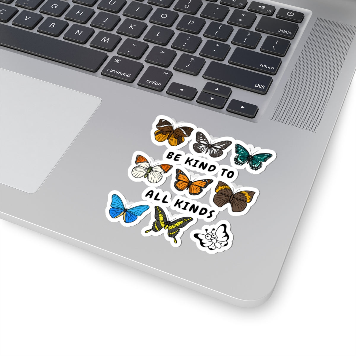 laptop with a "be kind to all kinds" butterfly sticker on a white background