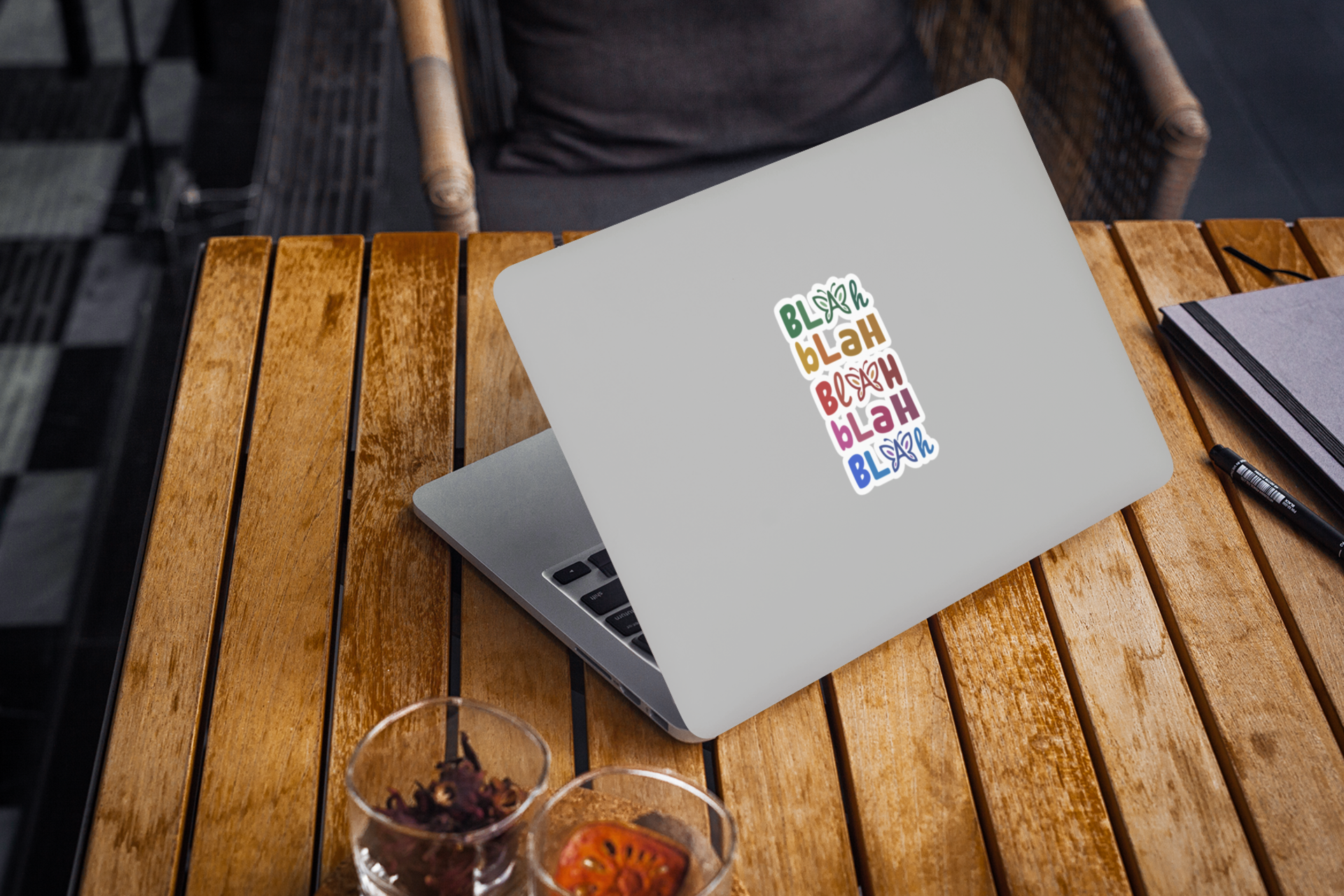 Laptop with colorful “Blah Blah Blah” sticker centered on the lid on a wooden table.