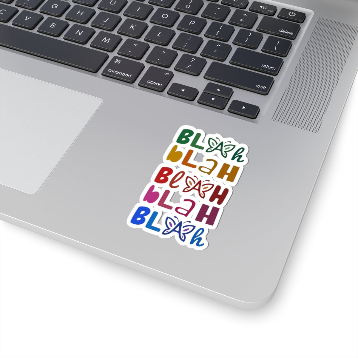Close-up of the colorful 'Blah Blah Blah' sticker on a laptop near the trackpad.
