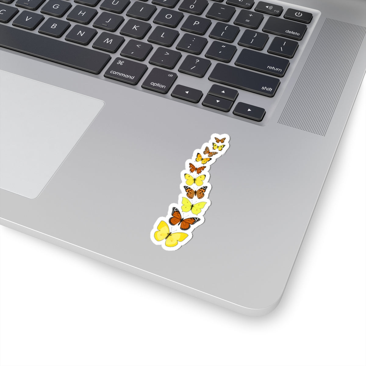 Yellow butterfly vinyl sticker decorating a silver laptop near the keyboard.