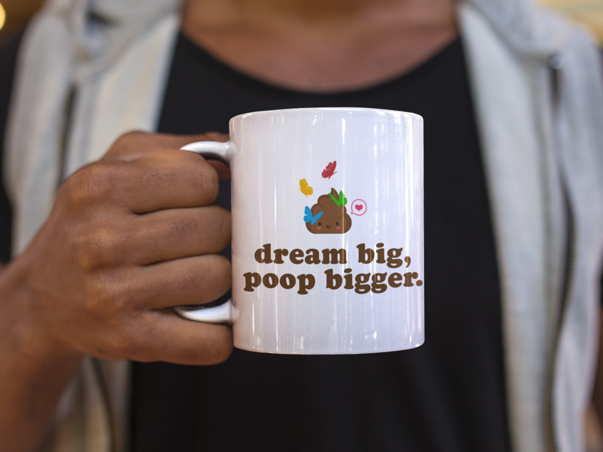 man holding a "dream big, poop bigger" ceramic coffee mug during coffee break
