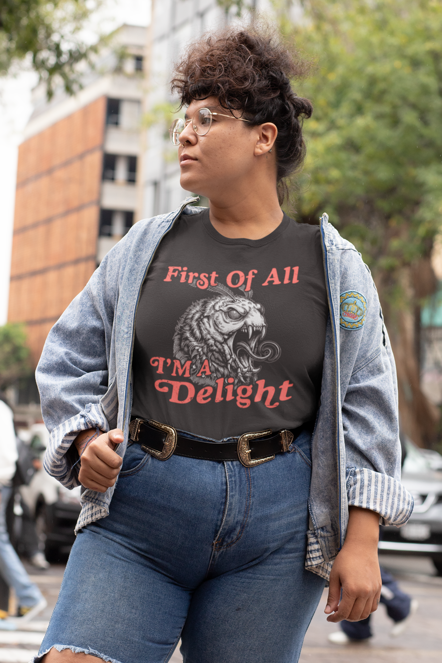Woman wearing a black First Of All I’m a Delight monster moth t-shirt styled casually outdoors with jeans and a sweater.