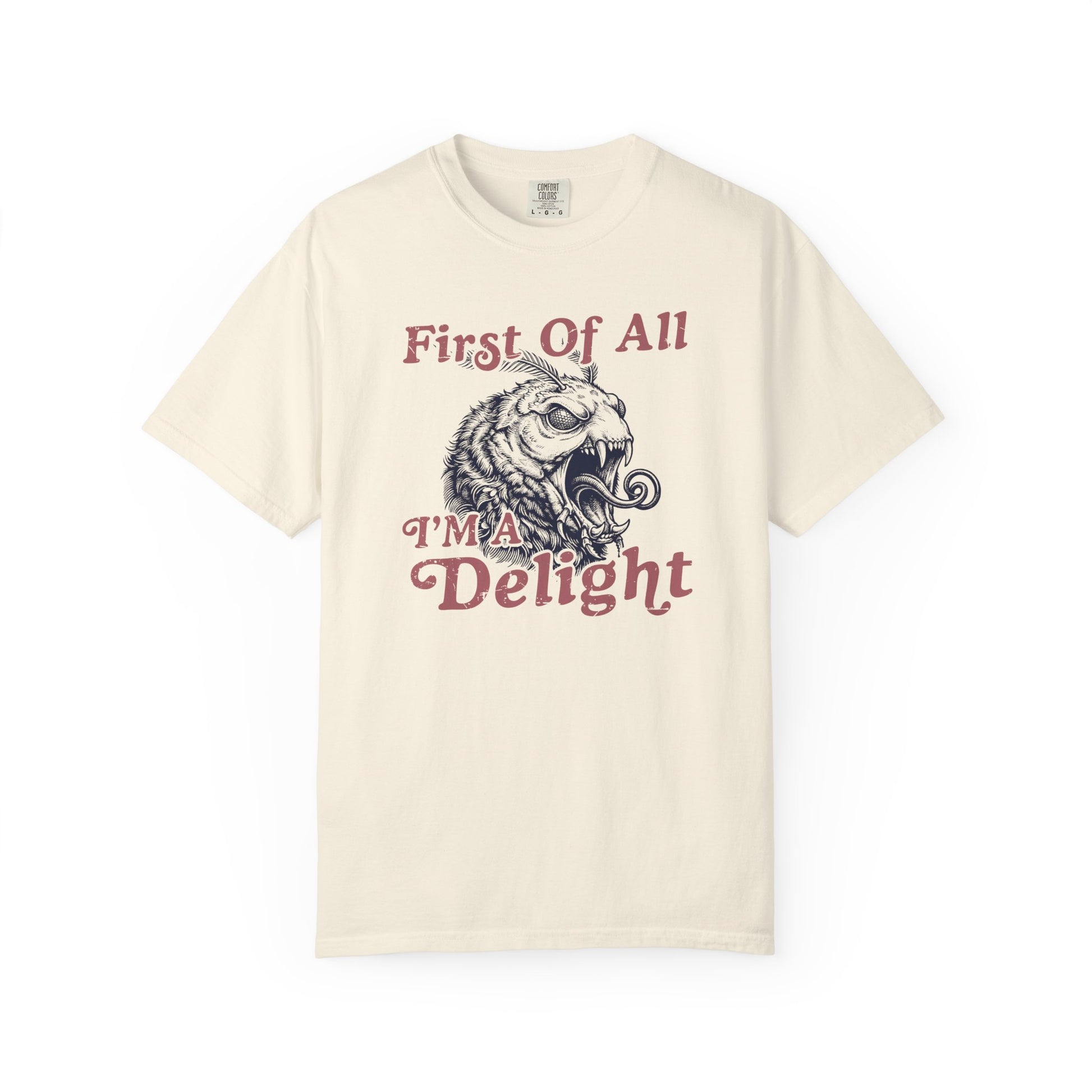 Cream graphic t-shirt with coral vintage lettering and a detailed monster moth design reading First Of All I’m a Delight.