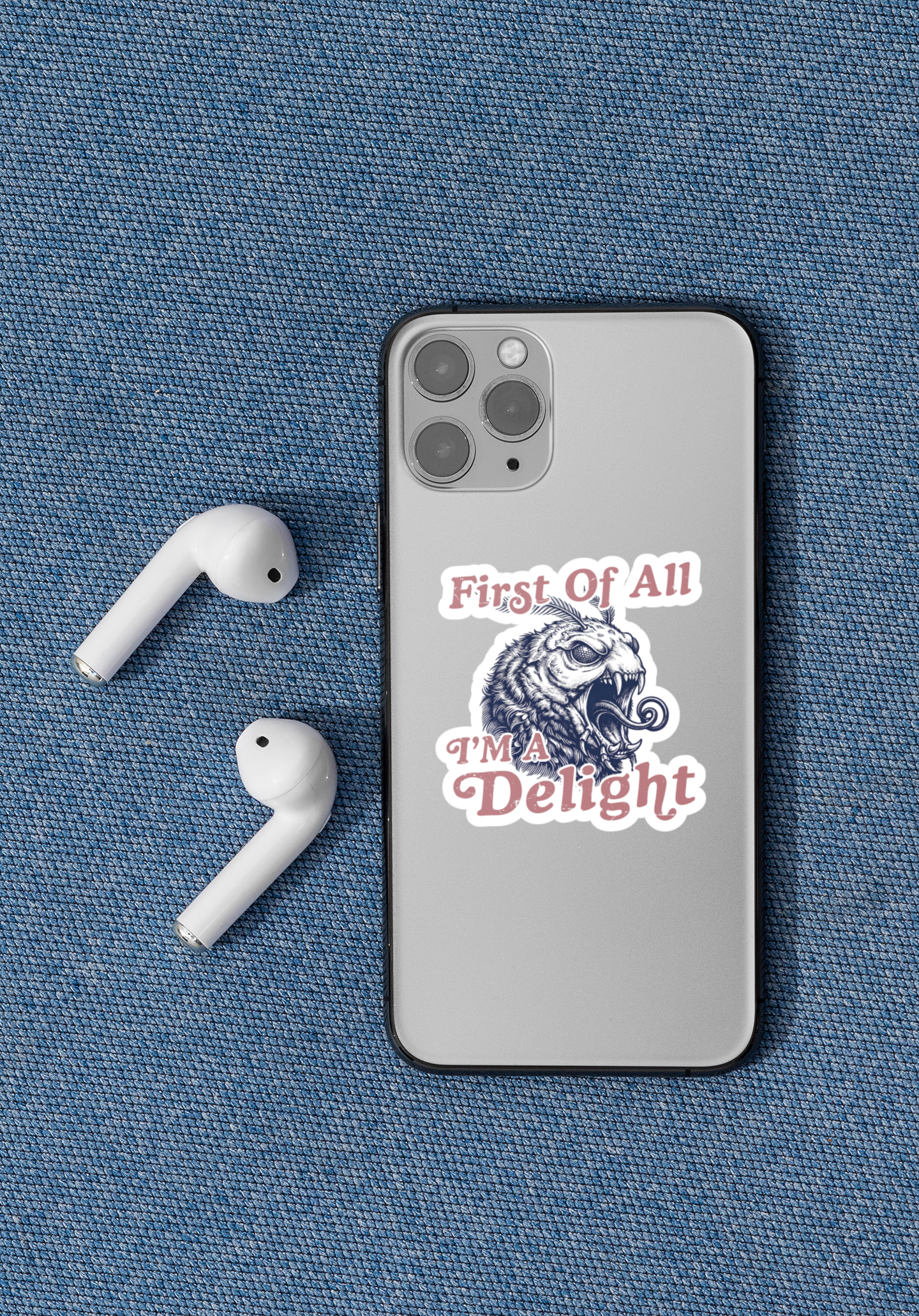 First Of All I’m a Delight monster moth sticker applied to a smartphone next to wireless earbuds.