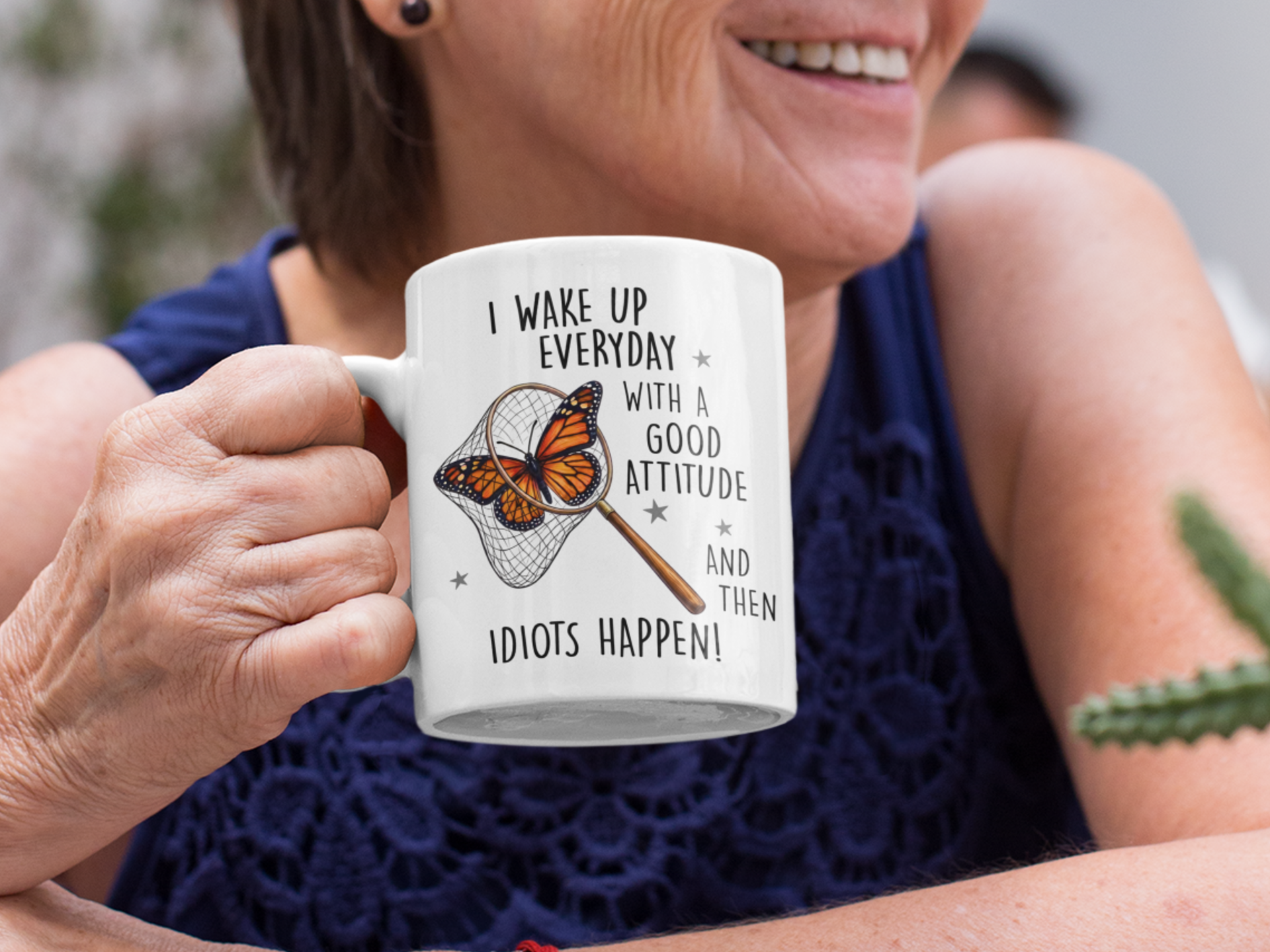 Woman holding funny butterfly mug with sarcastic quote and butterfly net graphic, outdoors.