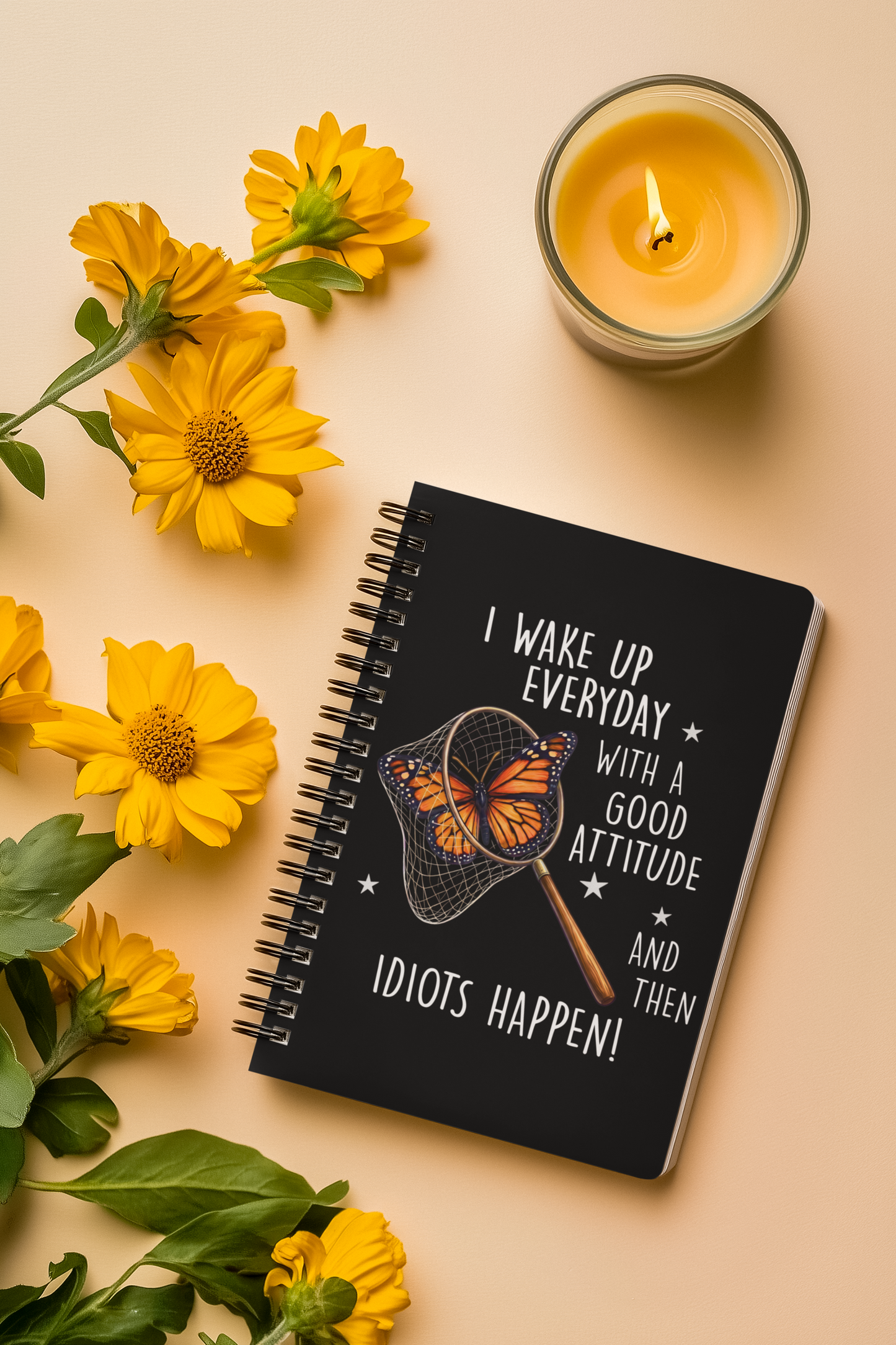 Funny butterfly spiral notebook shown in a styled flat lay with flowers and candle on a beige background