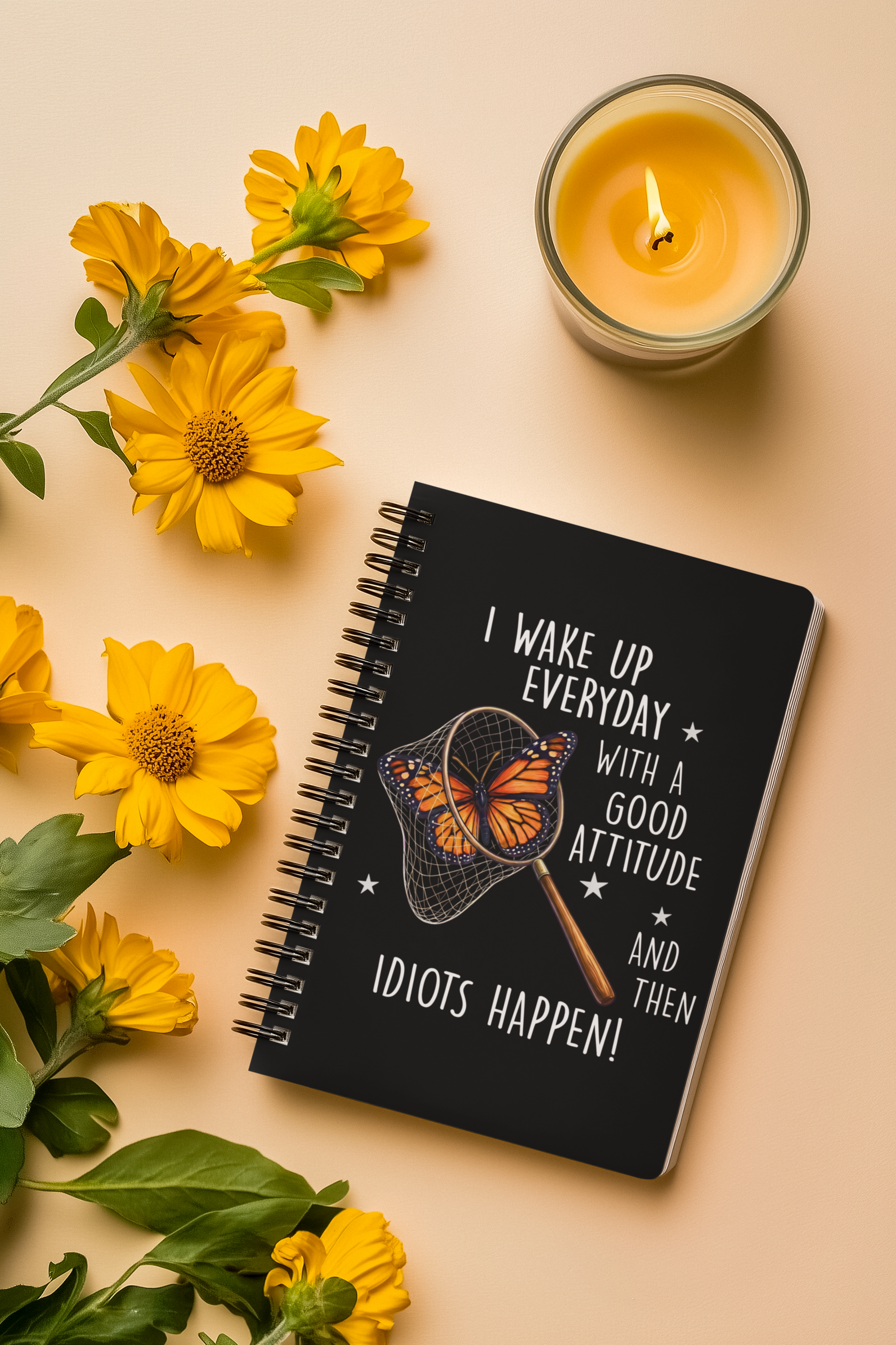 Funny butterfly spiral notebook shown in a styled flat lay with flowers and candle on a beige background