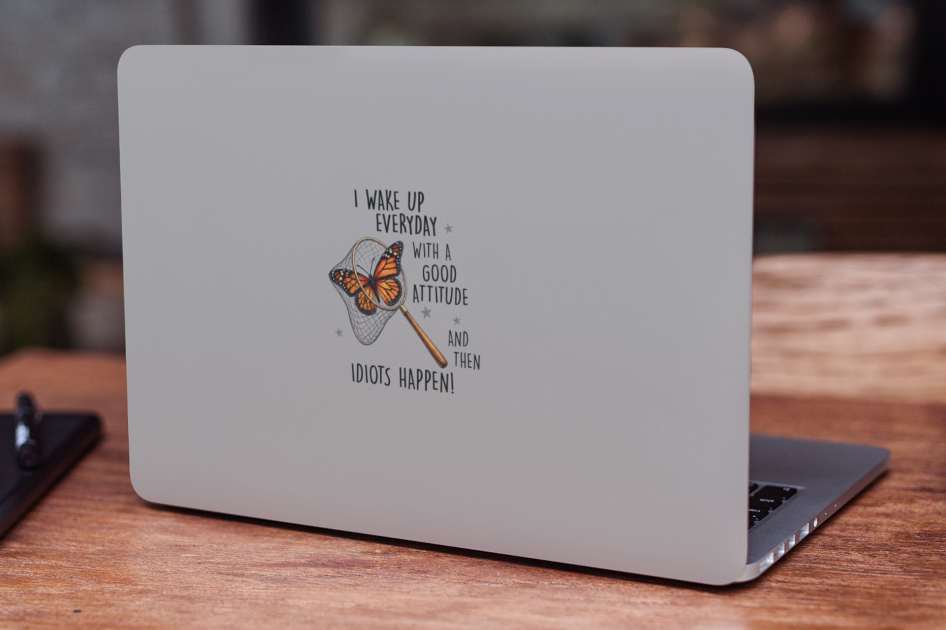Funny butterfly vinyl decal shown on the back of a laptop on a wooden surface