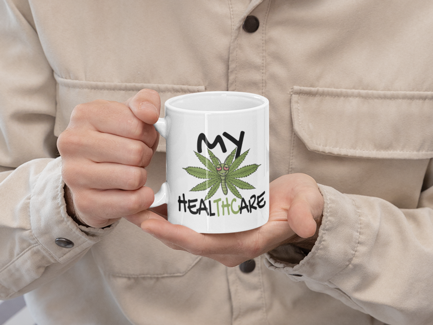Person holding a white My Healthcare cannabis butterfly mug with a funny marijuana healthcare design for cannabis lovers and stoner gifts.