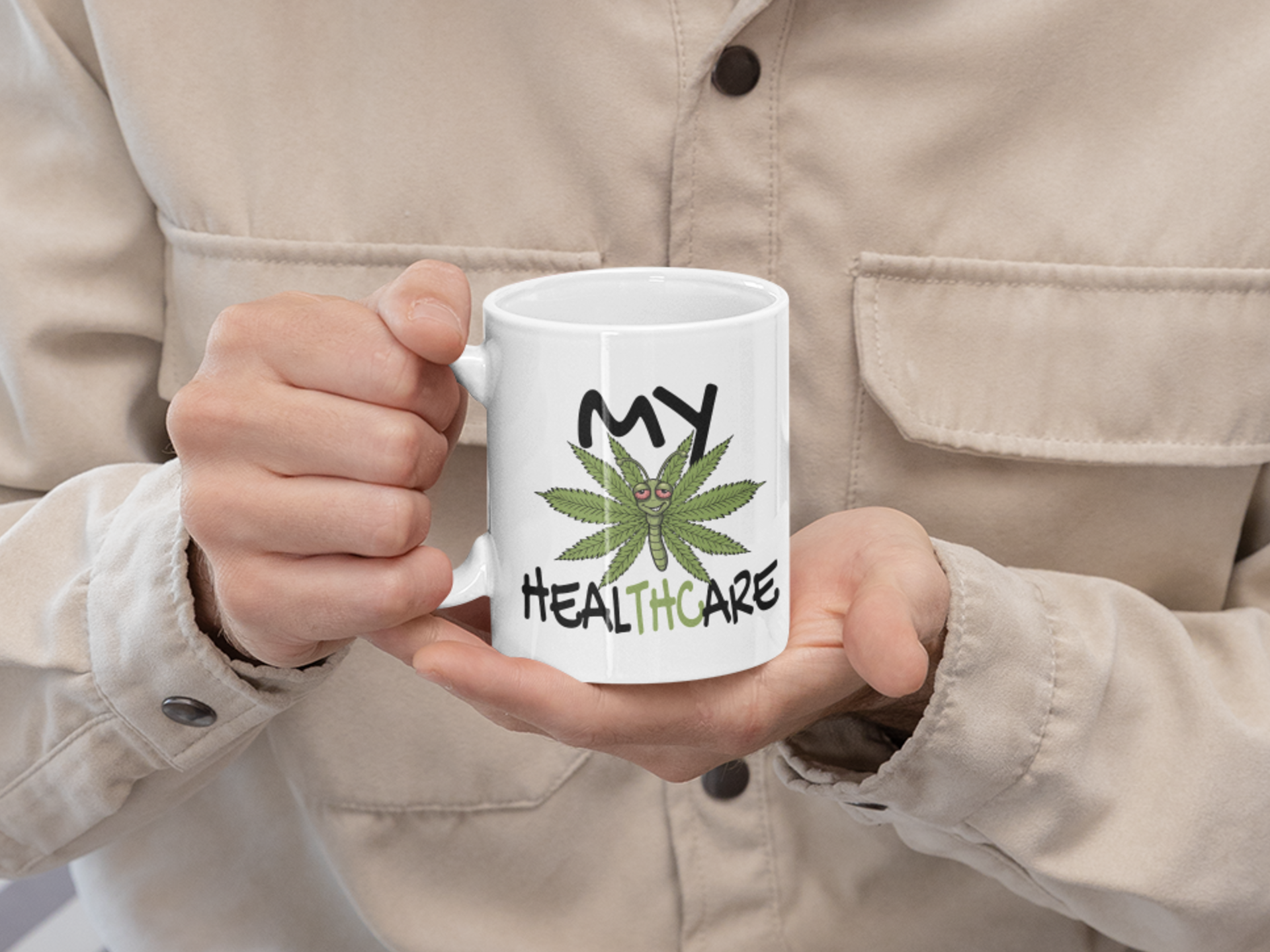 Person holding a white My Healthcare cannabis butterfly mug with a funny marijuana healthcare design for cannabis lovers and stoner gifts.