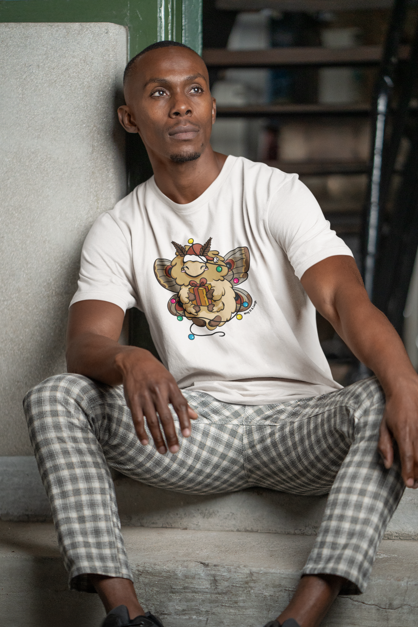 Man in white eco friendly holiday moth tee, sitting on the ground