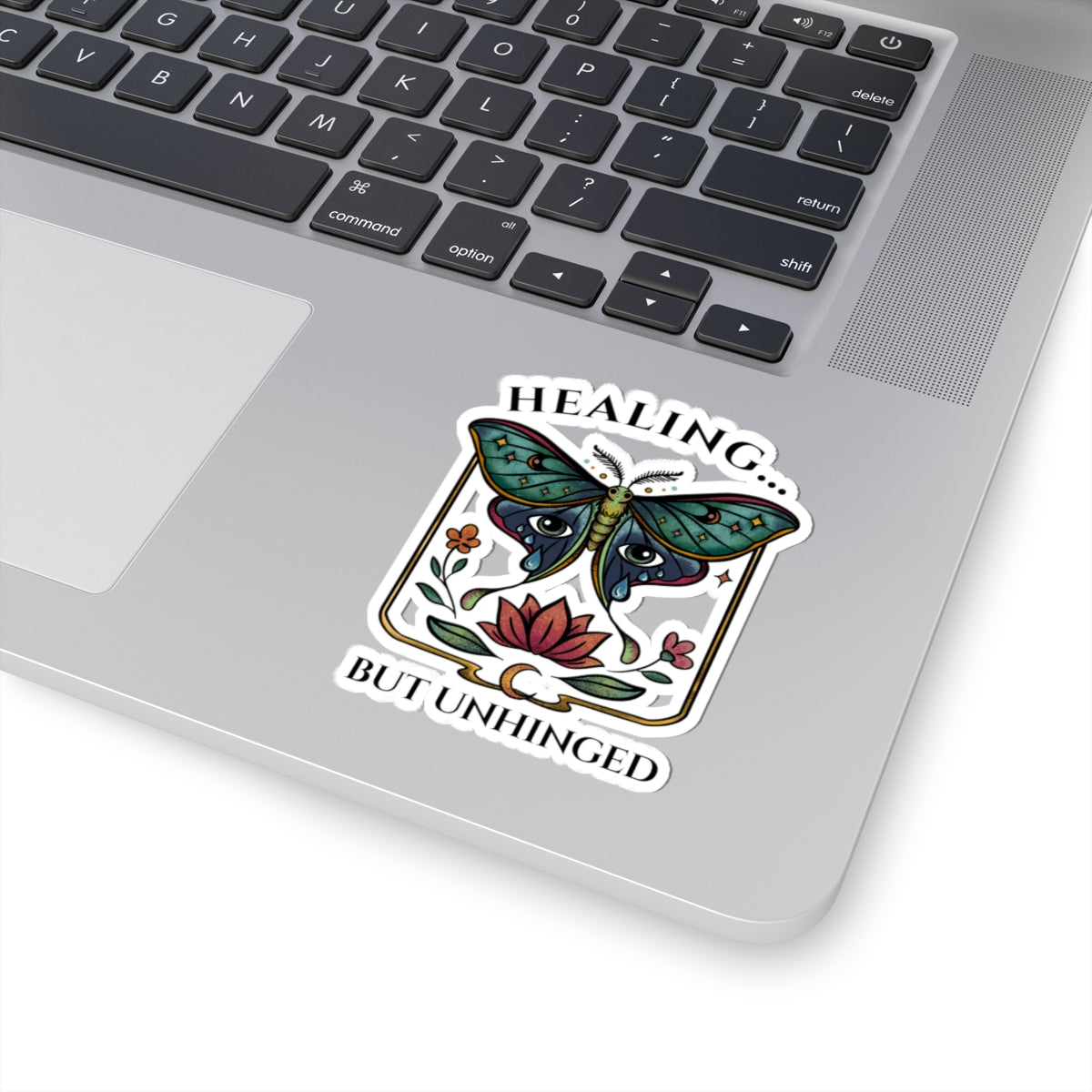 laptop with a decorative sticker featuring a butterfly and text on the palm rest area