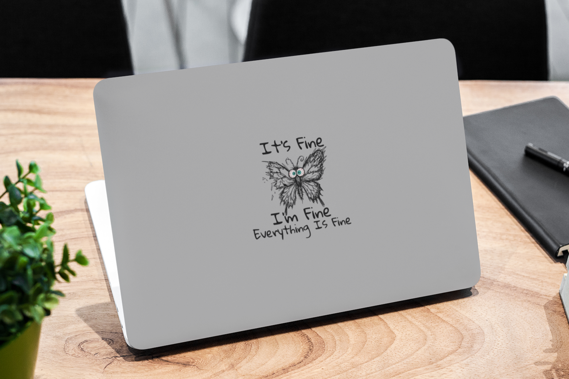 Anxious butterfly vinyl sticker on laptop featuring It's Fine I'm Fine Everything Is Fine text on a wooden desk