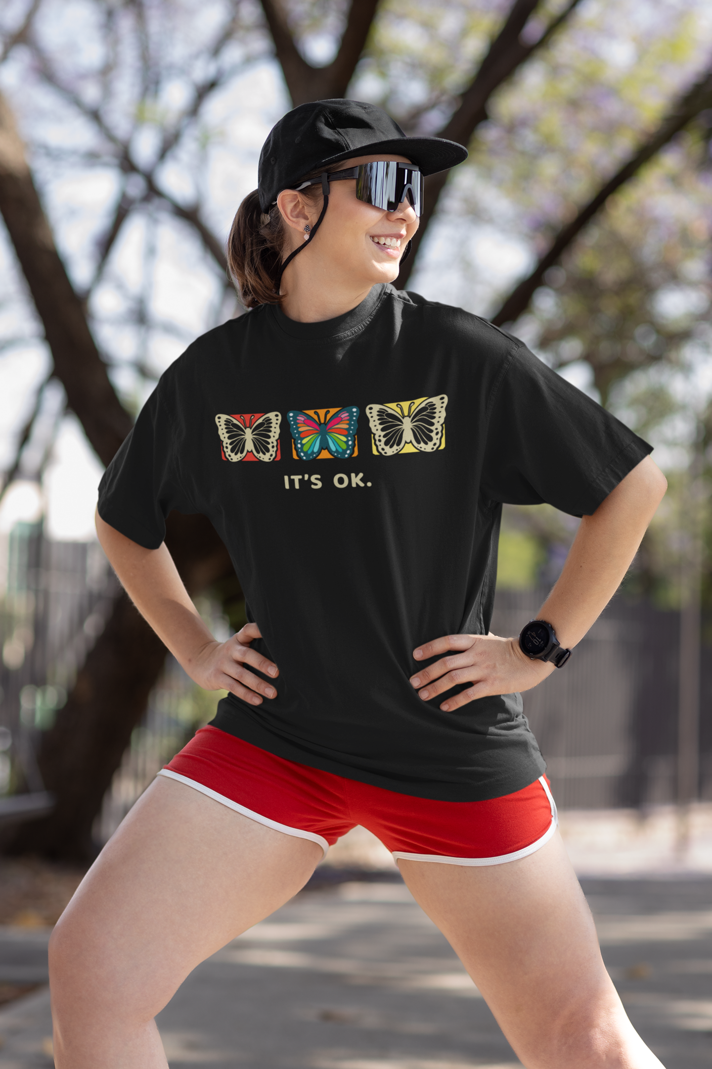 a happy female fashion model stretching her legs before running wearing an It’s OK butterfly tee