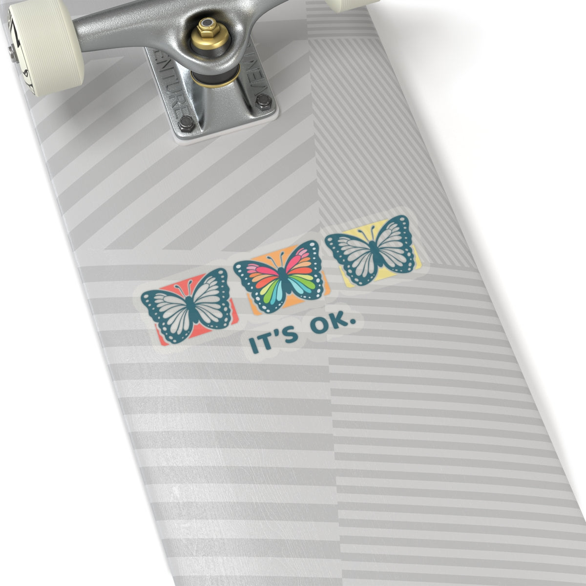 'it's ok' butterfly sticker on a skateboard deck, indoor lifestyle view