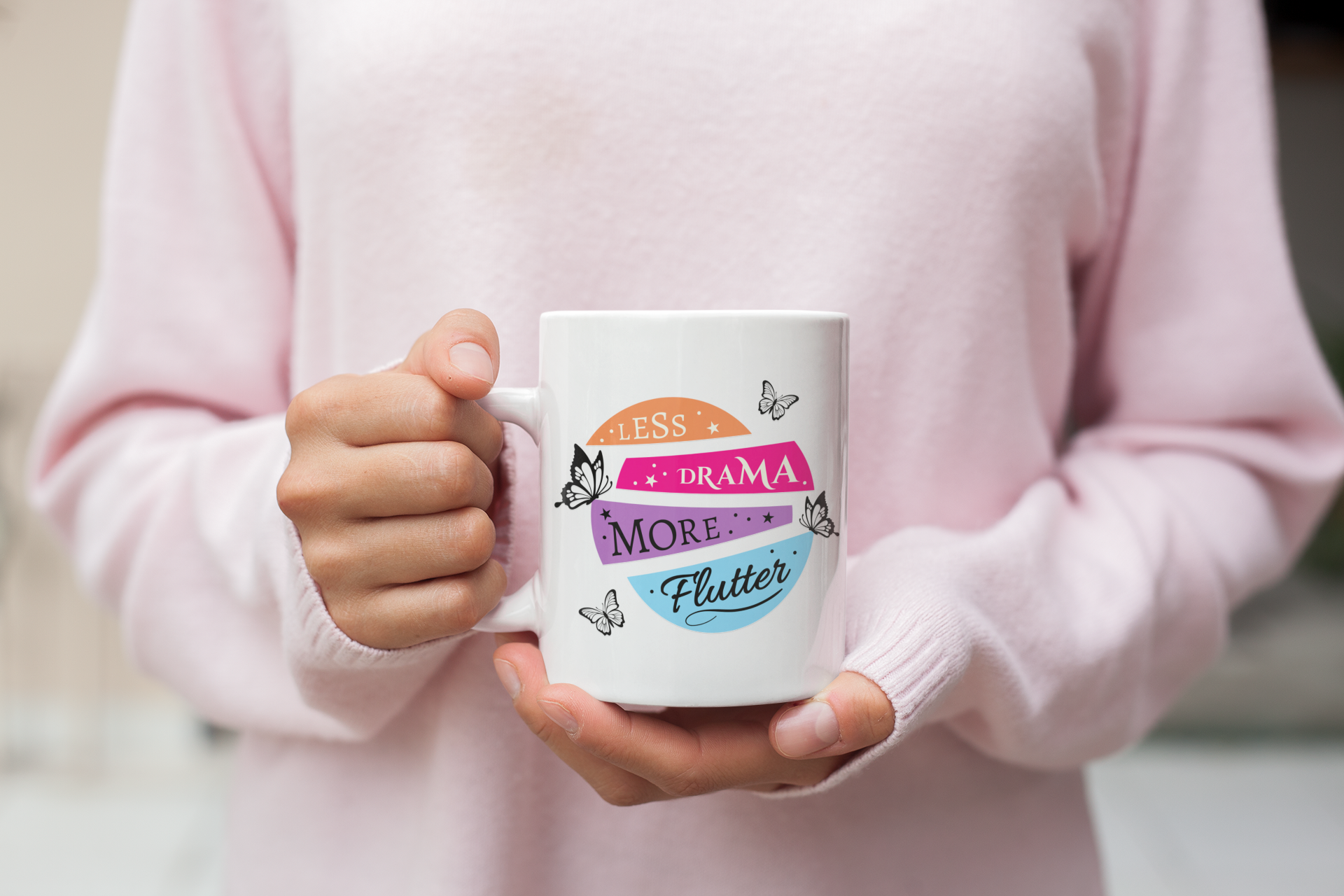 female hand holding a white 11oz “less drama more flutter” butterfly coffee mug