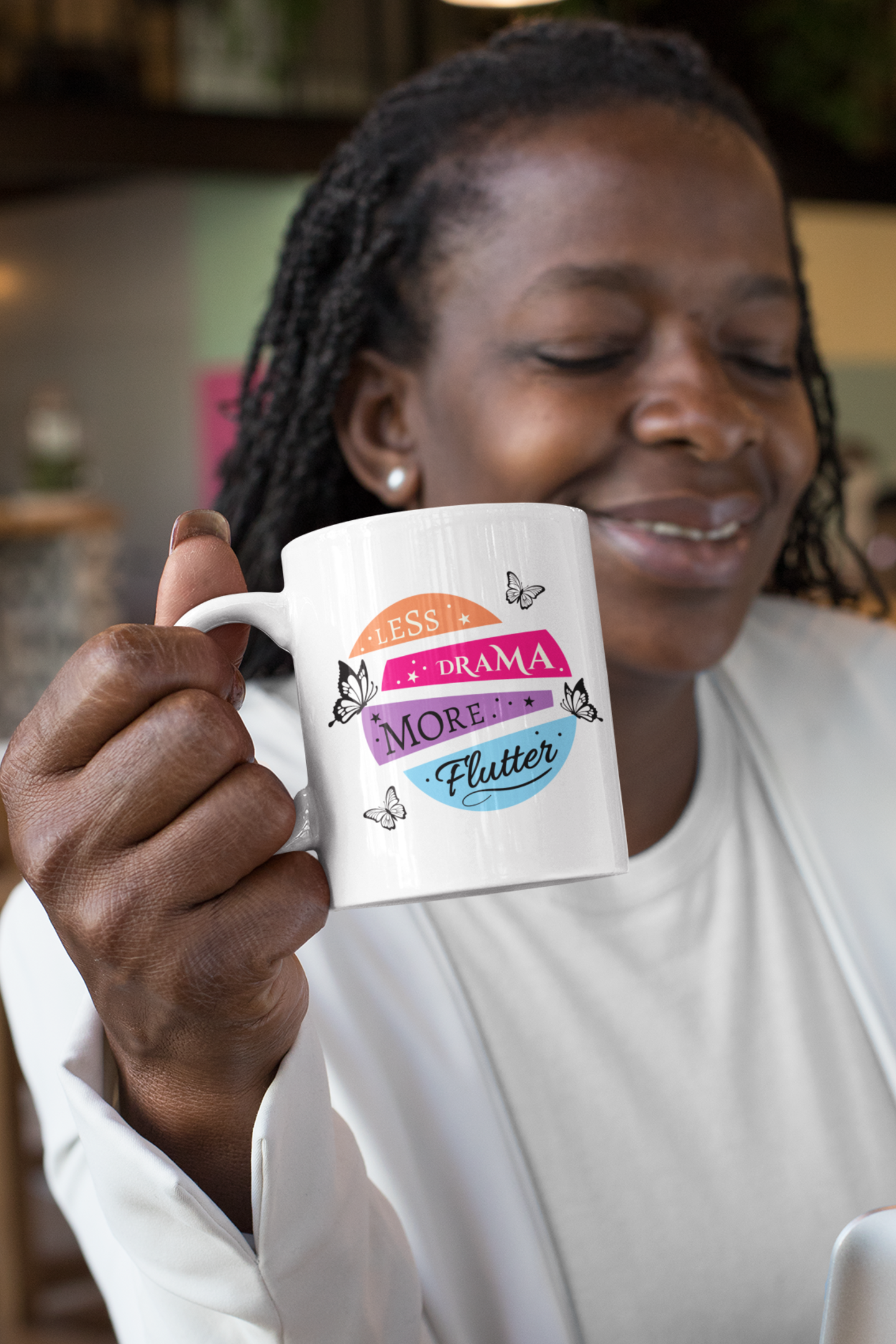 woman drinking coffee in a white 11 oz “less drama more flutter” butterfly mug at a coworking space