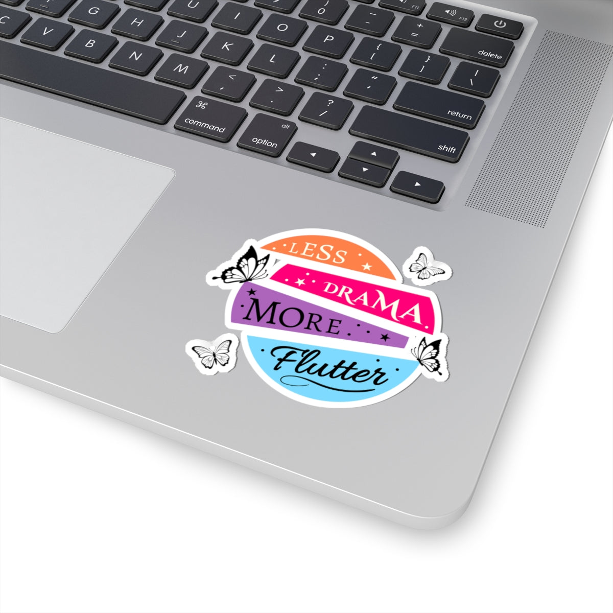 laptop with a colorful black butterflies sticker reading 'less drama more flutter' on a white background