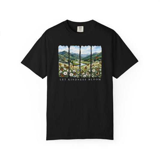 Black unisex garment-dyed t-shirt featuring a floral mountain landscape with butterflies and the phrase Let Kindness Bloom on a white background