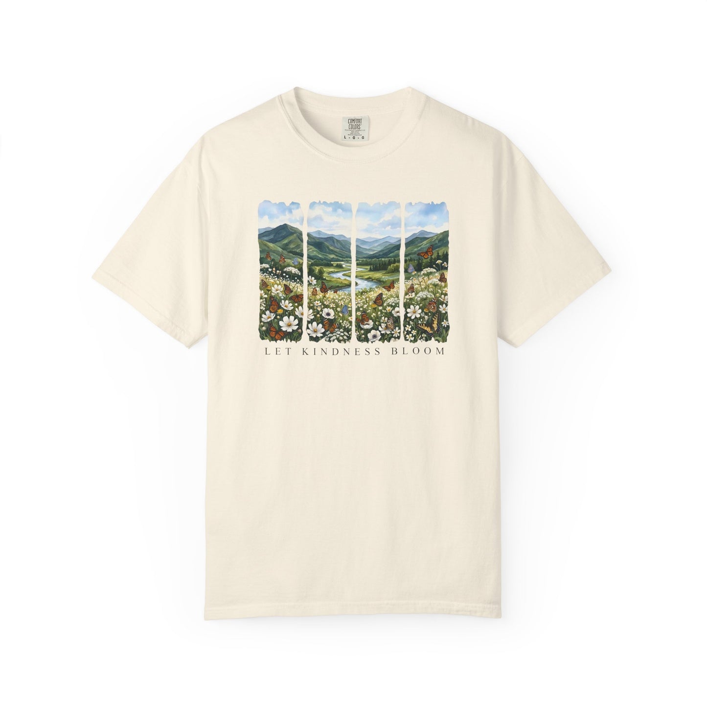 Cream t-shirt featuring a Let Kindness Bloom butterfly floral landscape graphic on the chest on a white background