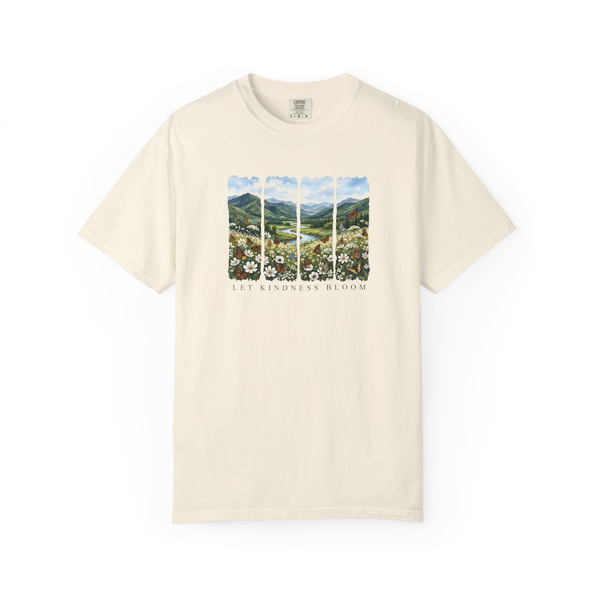 Ivory Comfort Colors t-shirt featuring a Let Kindness Bloom butterfly floral landscape graphic on the chest