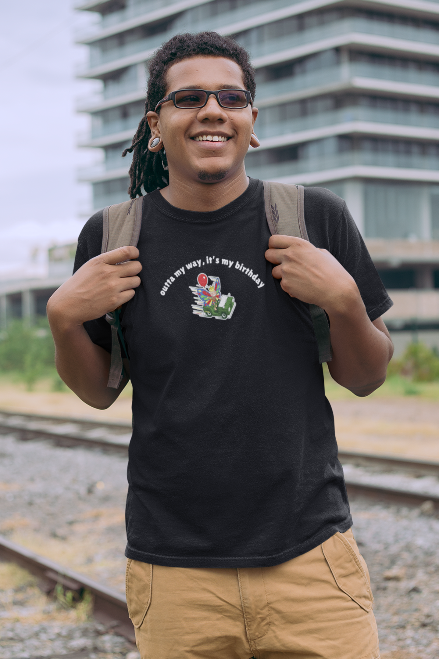 Man wearing a black butterfly birthday graphic t-shirt featuring the phrase "Outta My Way, It's My Birthday" in an outdoor lifestyle setting.