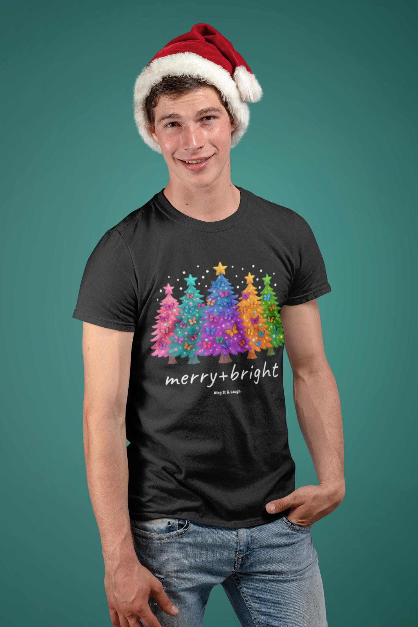 Man wearing a black t-shirt with colorful Christmas trees and 'merry+bright' text, paired with a Santa hat on a teal background.