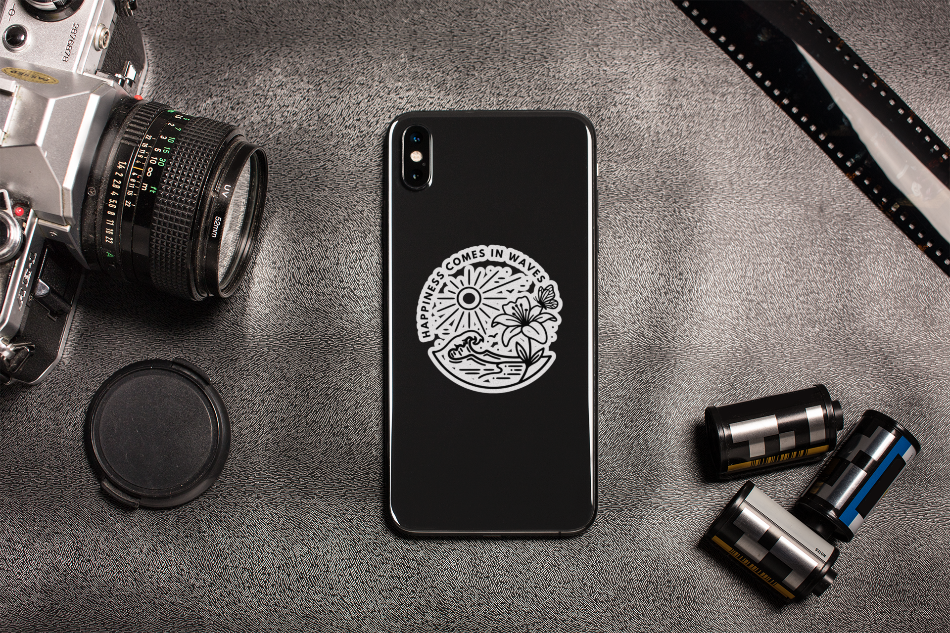 Happiness Comes in Waves beach butterfly sticker applied to phone in lifestyle flat lay
