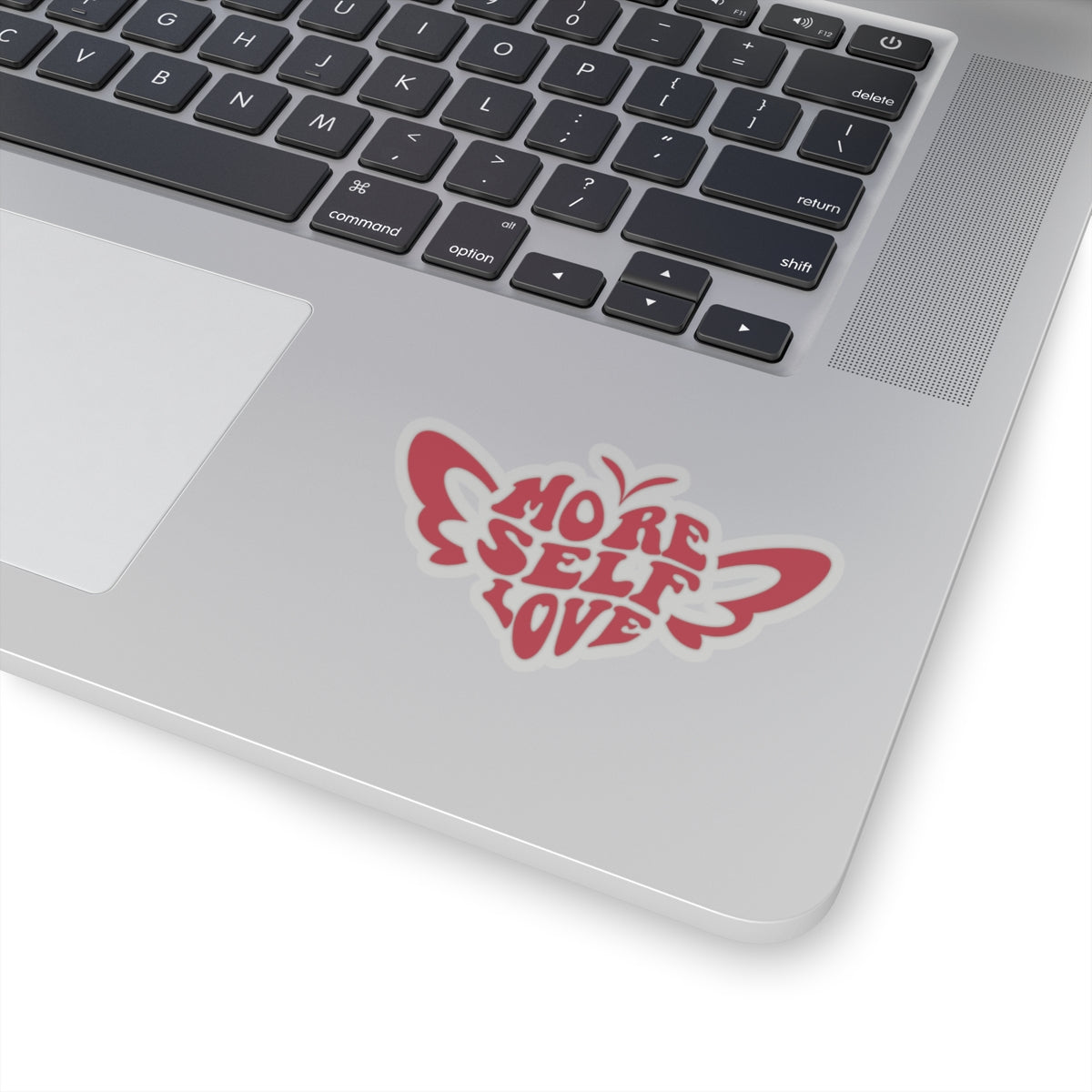 Laptop with a red More Self Love butterfly vinyl sticker on the palm rest area