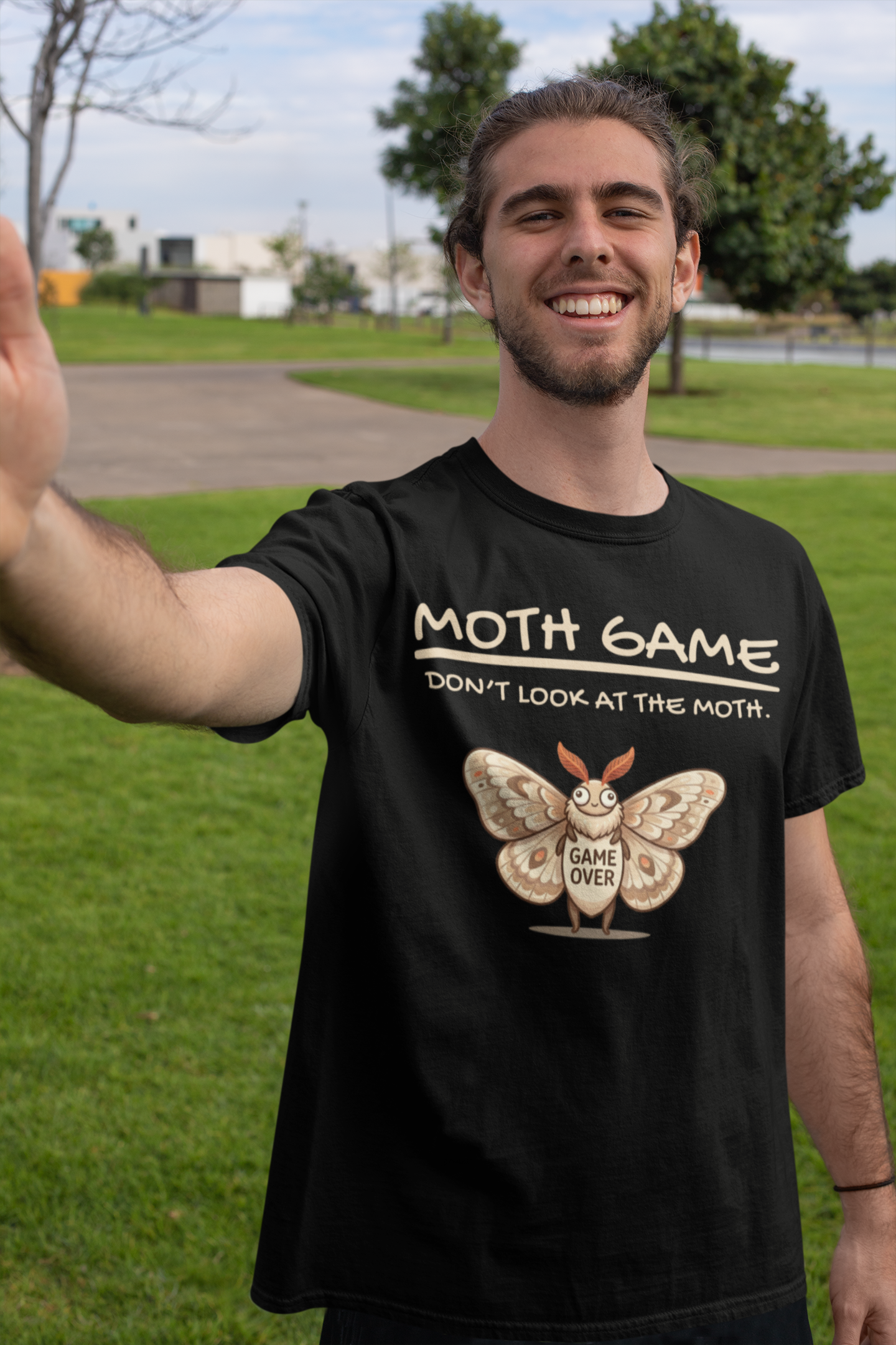 Man wearing a black Moth Game Don’t Look At The Moth t-shirt with cute moth gaming humor graphic, standing outdoors.