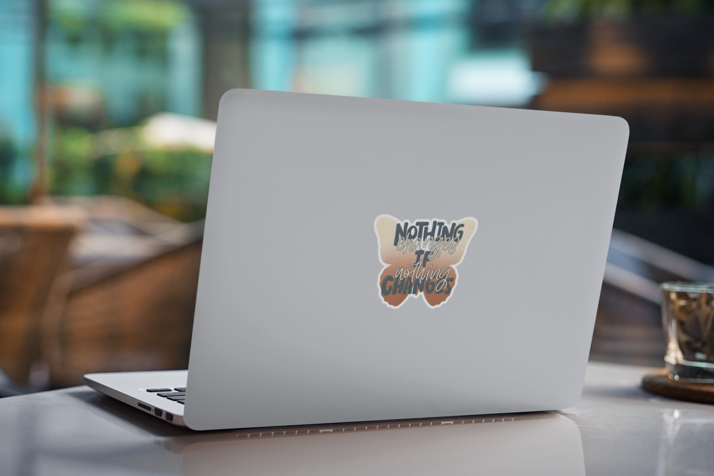 Laptop with an inspirational butterfly sticker with motivational change quote on a blurred indoor background 
