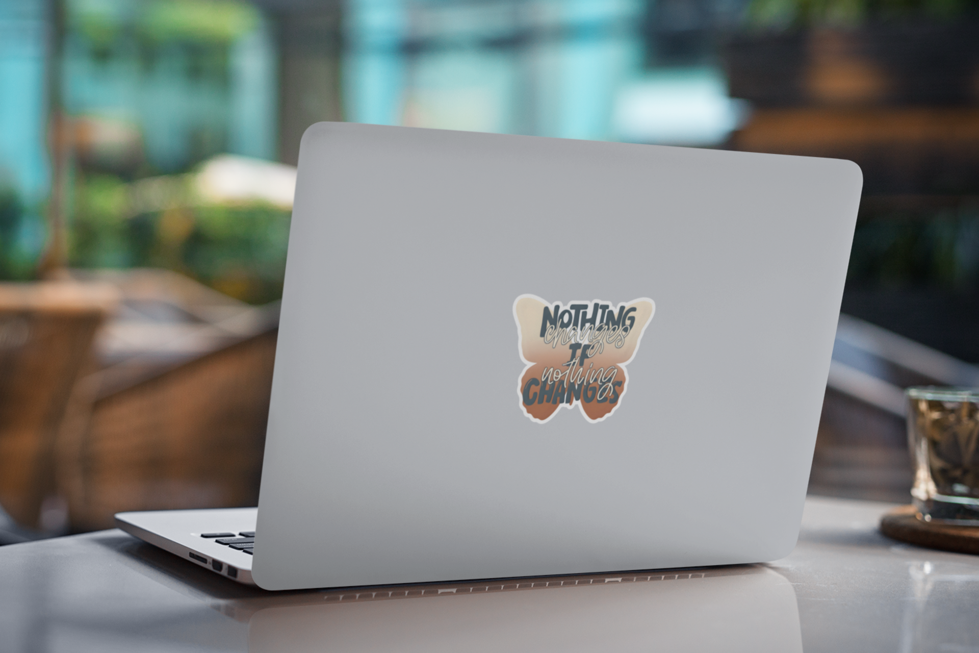 Laptop with an inspirational butterfly sticker with motivational change quote on a blurred indoor background 