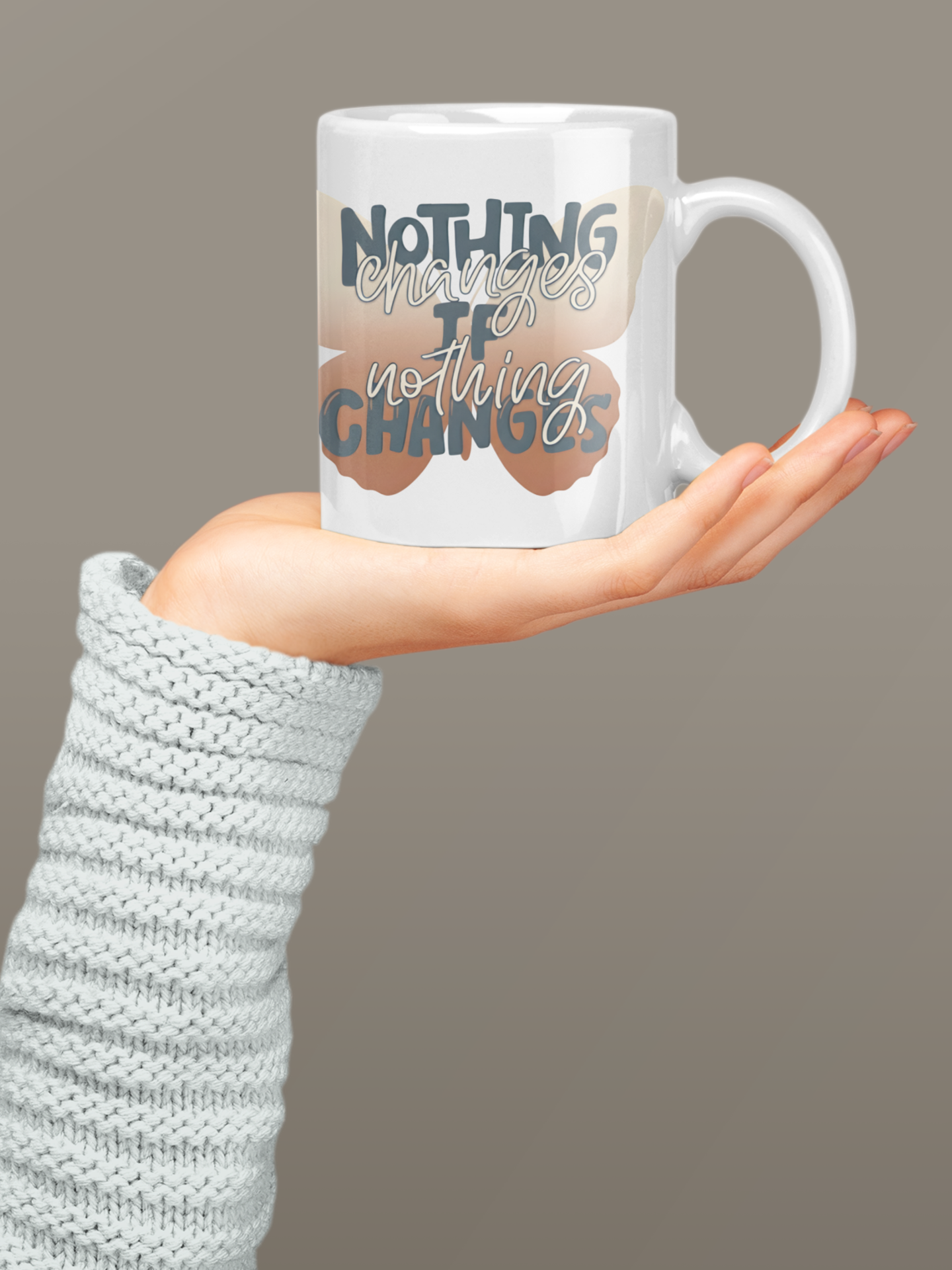 Motivational butterfly coffee mug featuring the quote "Nothing Changes If Nothing Changes" held by a person wearing a textured sleeve against a plain background