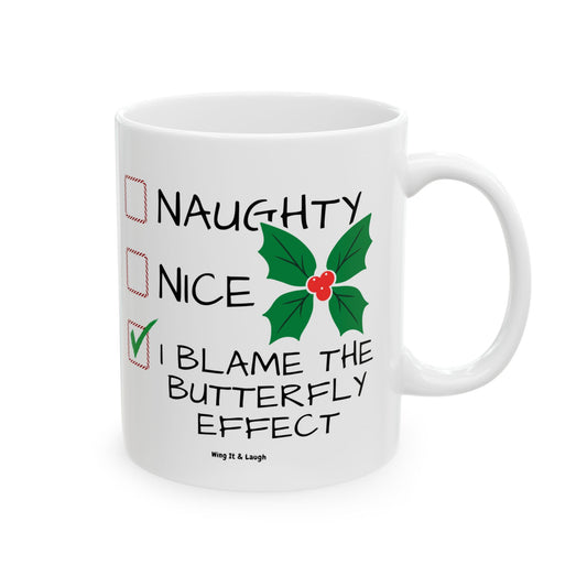 White ceramic Christmas coffee mug with “Naughty, Nice or I Blame the Butterfly Effect” design on a white background