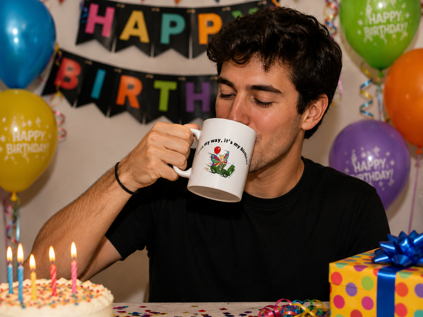 Person drinking from a funny butterfly birthday mug during a birthday celebration with balloons, cake, and gifts.
