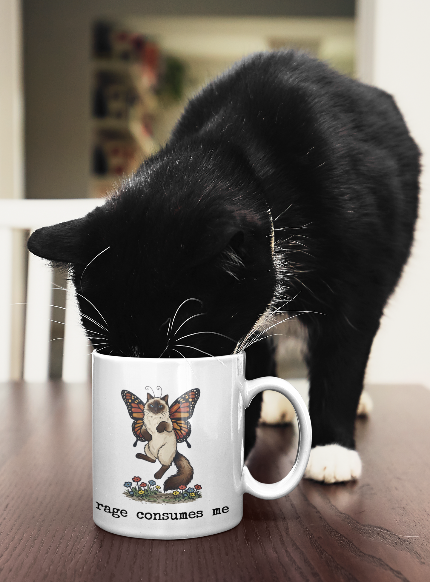 Black cat next to Rage Consumes Me funny cat mug on table