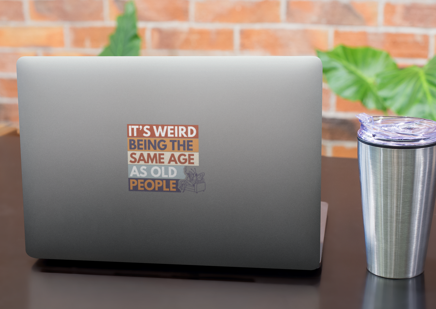 sarcastic butterfly sticker on laptop desk retro aging humor design next to a tumbler, with a brick wall and plants in the background.