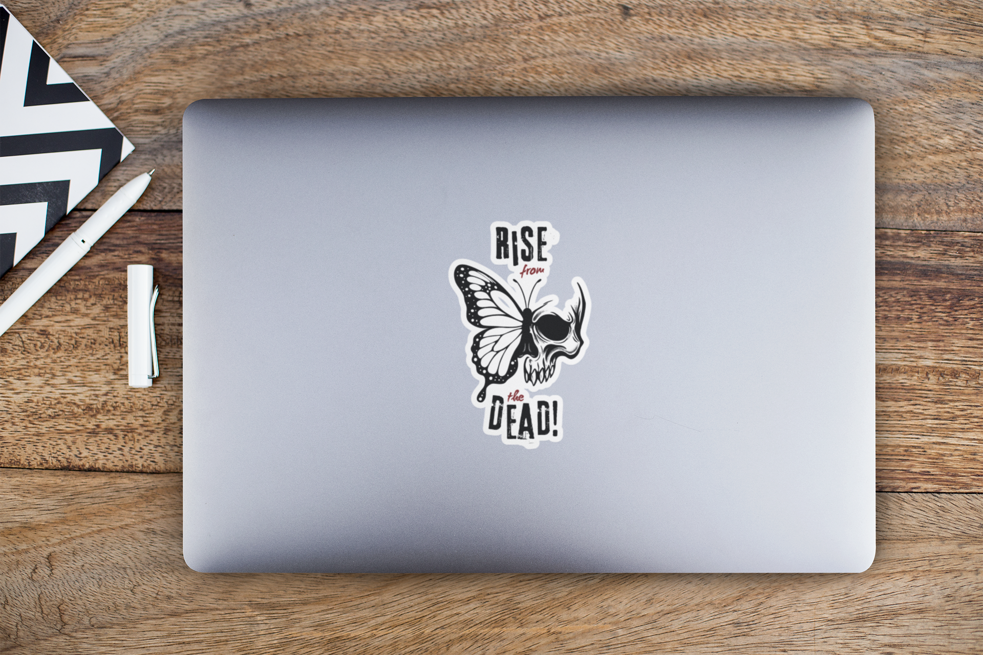 Skull-butterfly decal centered on silver laptop