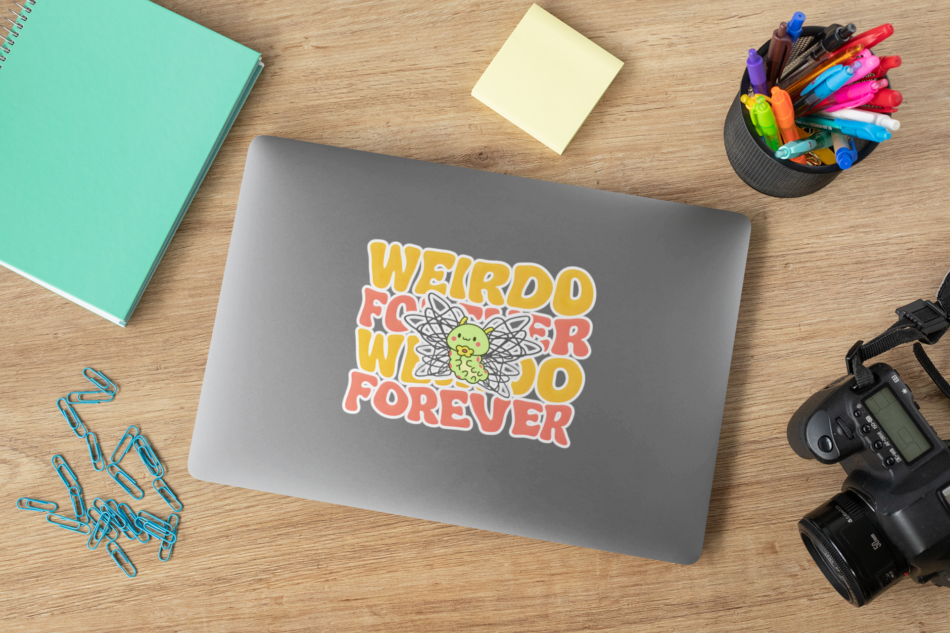 weirdo forever sticker on laptop with desk accessories—quirky aesthetic