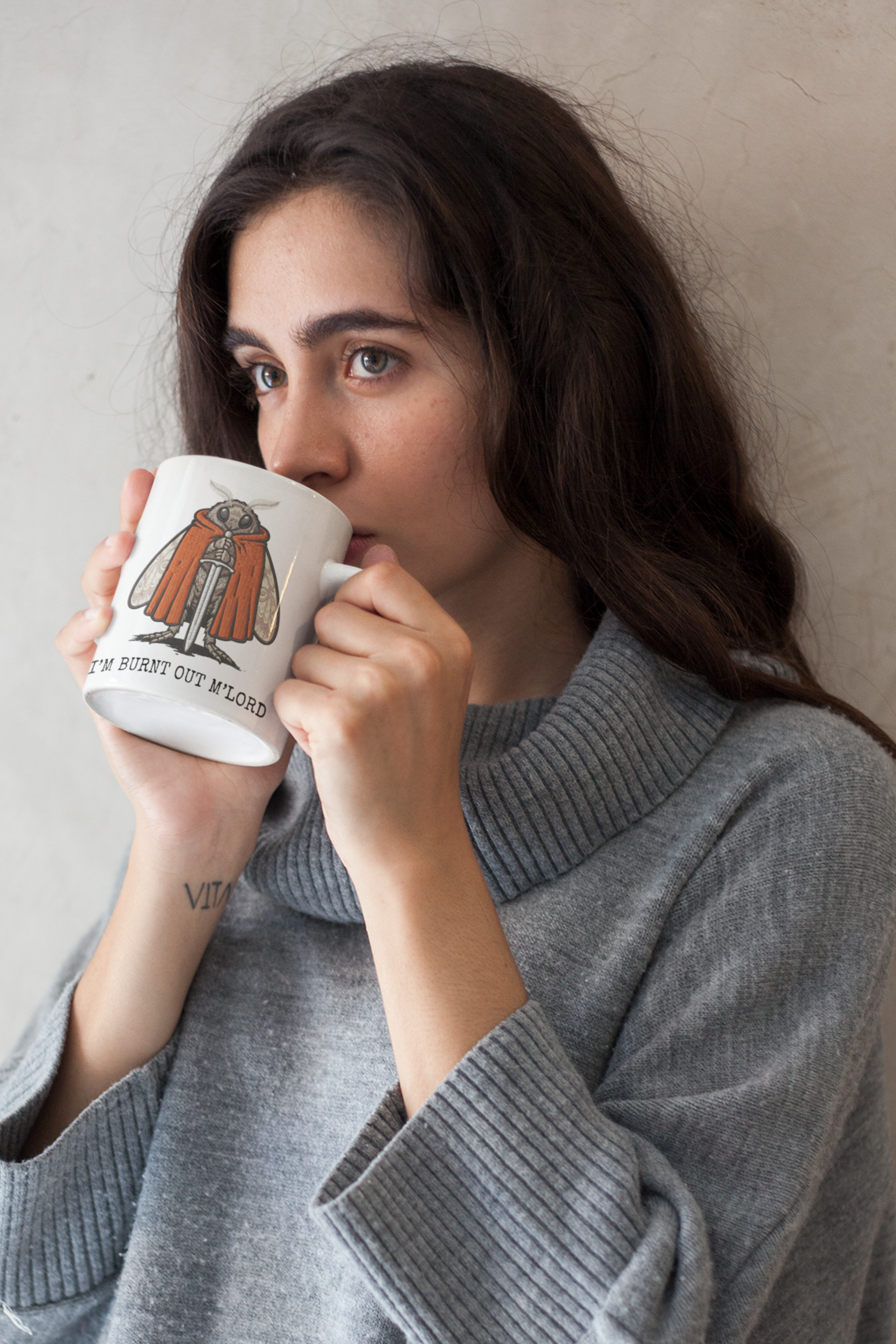 woman drinking coffee from funny moth meme mug with “I'm Burnt Out M'Lord” quote on a neutral background