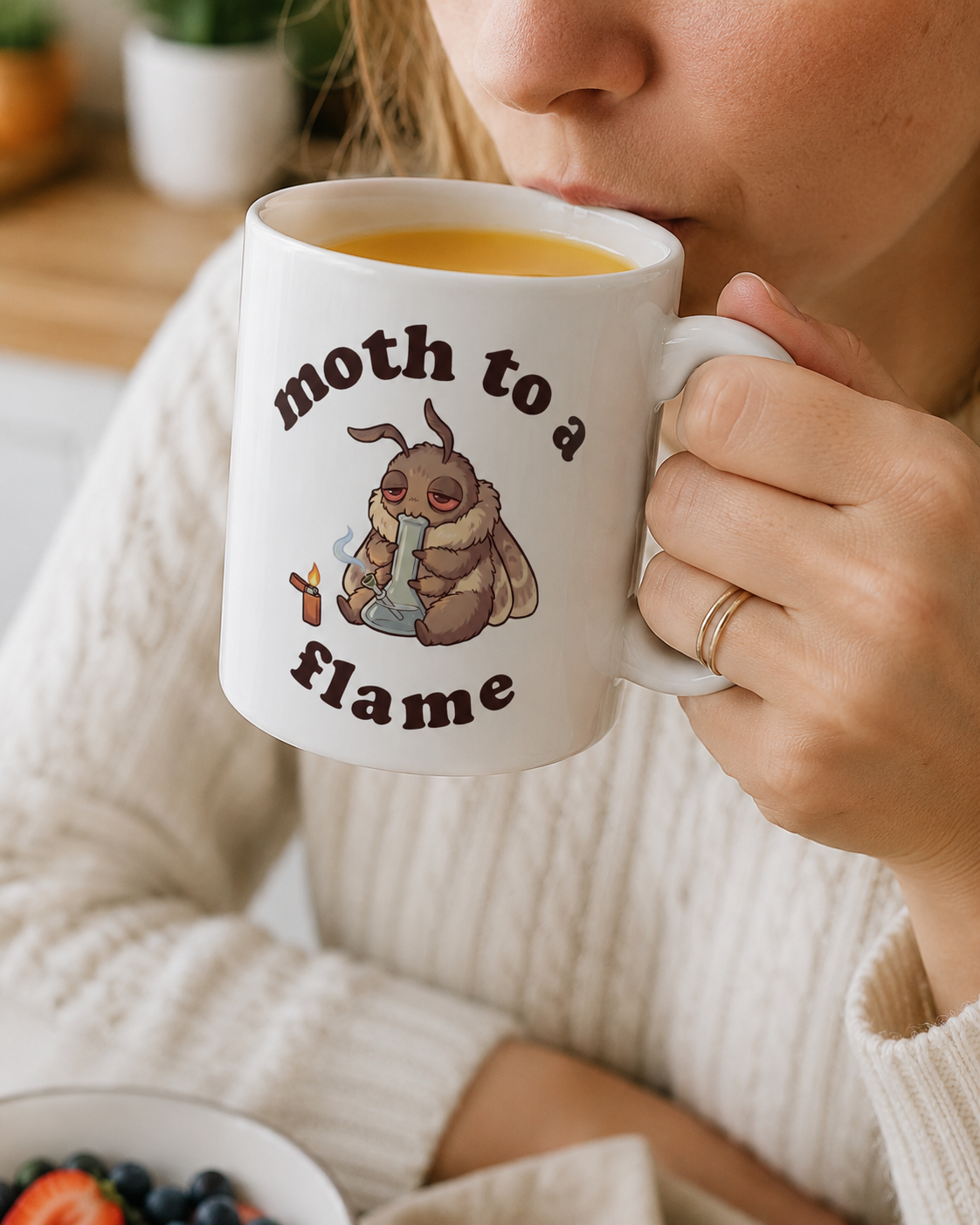 Person drinking from a Moth To a Flame cannabis coffee mug with cute stoner moth design, funny 420 gift cup for marijuana smokers.