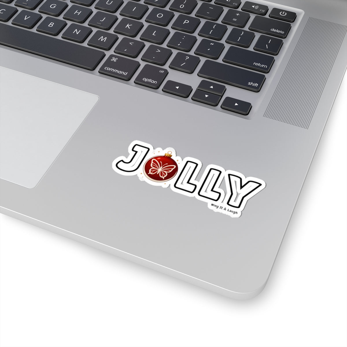 Laptop with a Xmas vinyl sticker featuring a white butterfly ornament and white 'Jolly' text on a white background
